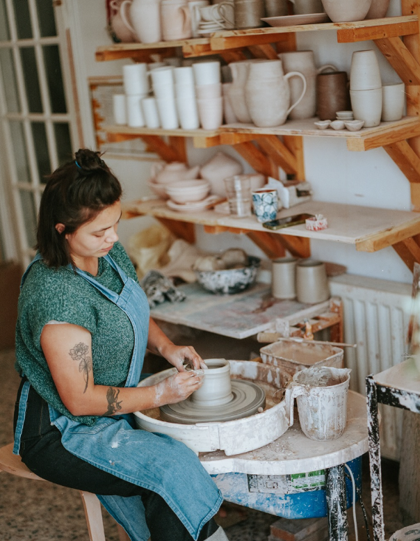 Ella Bua-In sitting at her potters wheel in her ceramic studio.