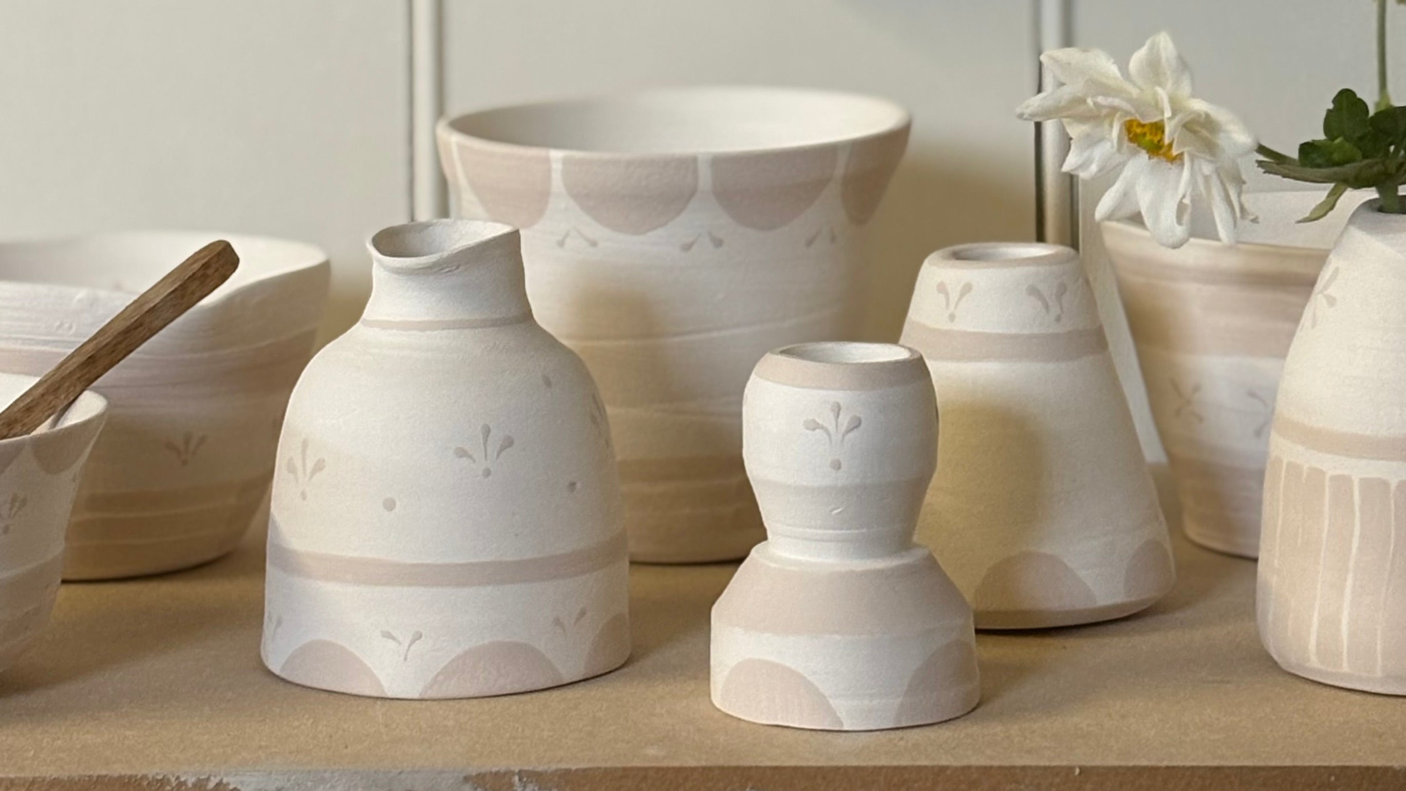 Collection of ceramic pots and vases on a wooden surface with a light background
