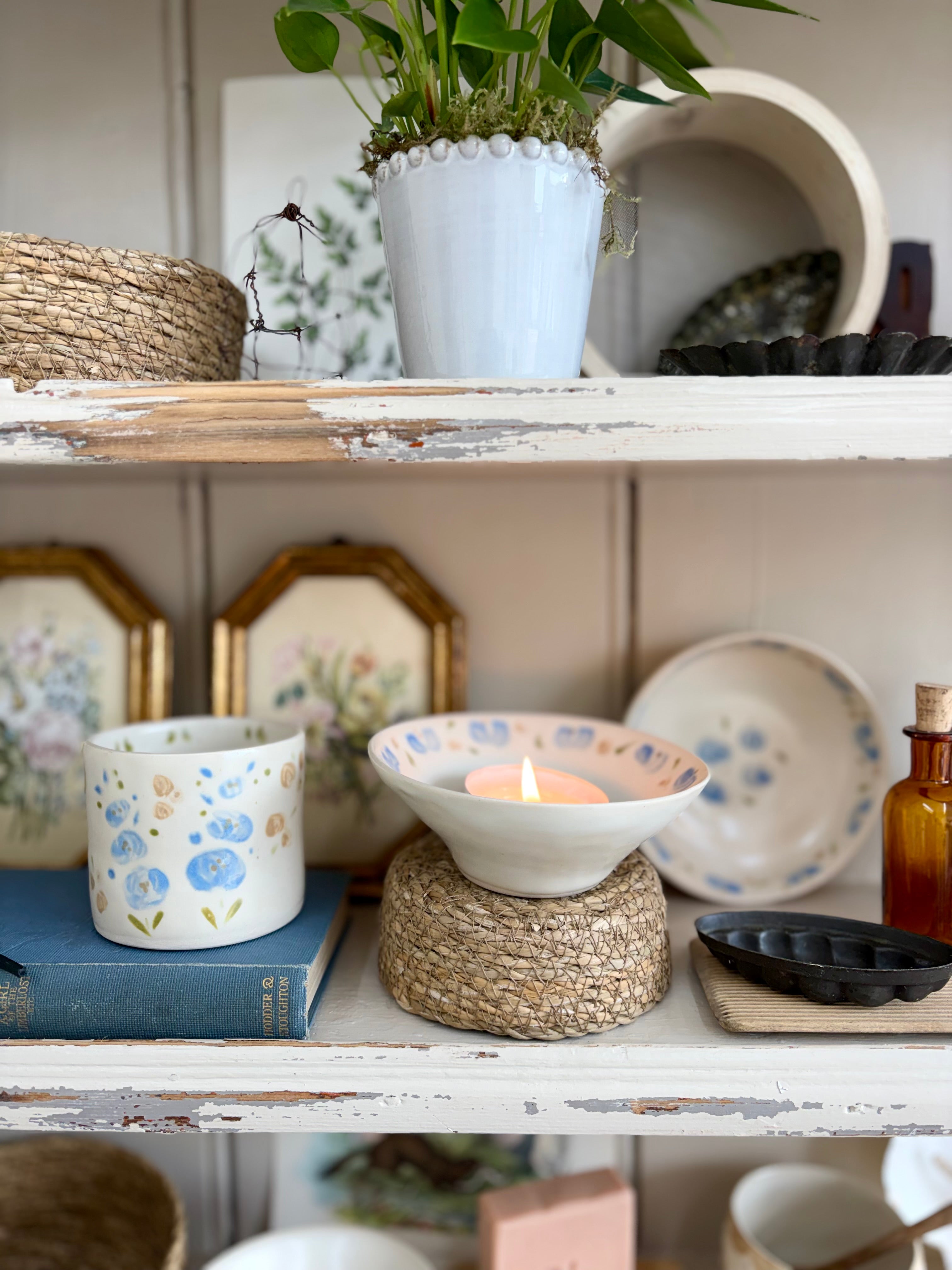 Shelf with decorative items including a candle, books, and a plant.